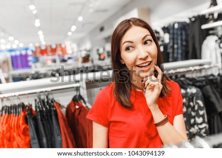 Portrait of a brunette woman, thinking about shopping clothes in the fashion clothes store. Making right choice concept