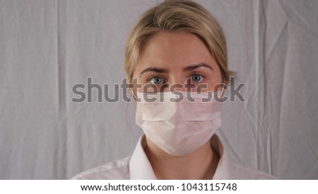 Portrait of a young beautiful female doctor, wearing glasses and wearing a medical mask, wearing blue rubber gloves.