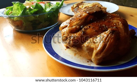 Roast whole chicken with mixed herbs on a blue plate and wooden table 