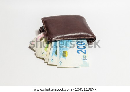 A brown leather purse and several shekel banknotes sticking out of it isolated on a white background