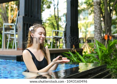 female woman holding group of stones, cairn balance in swimming pool sunlight. concept of meditation, yoga, healthy lifestyle, leisure and travel