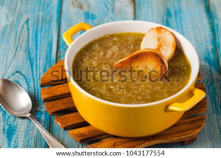 Classic onion soup with croutons. Served in yellow bowl on blue boards. Front view.