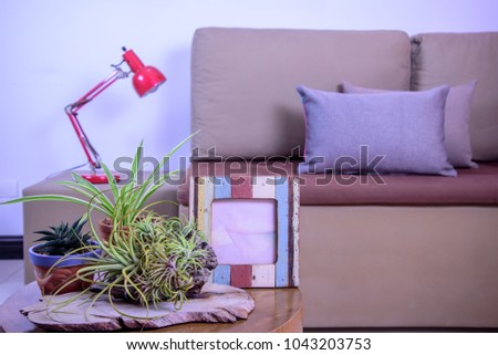 Still life of Living room with flower vase, photo frame on rustic wooden table over sofa background / Home decoration & lifestyle concept