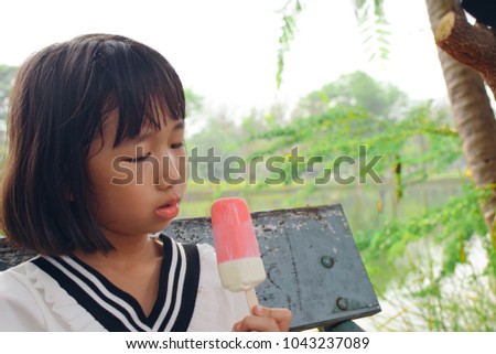Kid girl eating ice cream in the garden