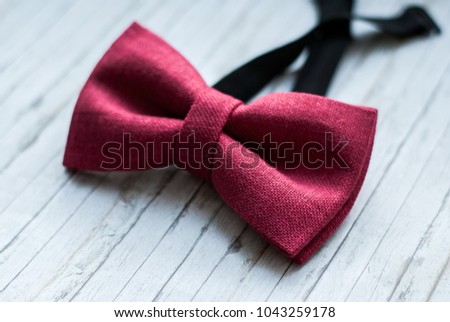 Red, marsala bow tie on a wooden background. Accessory for formal dress. Symbol of elegance and fashion for men. Men's casual. Men's and women's accessories. Men's and women's bowtie. Royalty-Free Stock Photo #1043259178