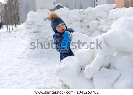 Boy building snow fortress at winter playground