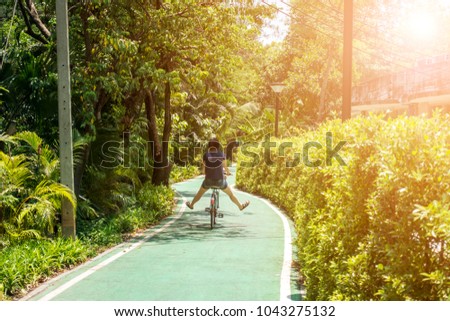 Happy young woman having fun riding a bicycle on sunny day in the park.