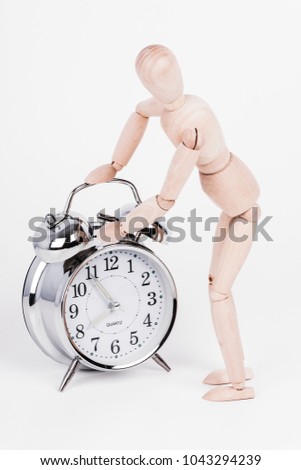 Wooden puppet is checking the alarm clock