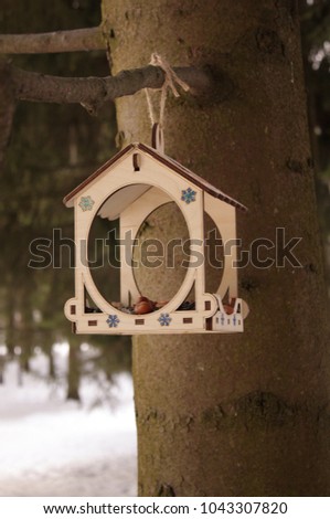 Self-made wooden bird feeder with nuts and seeds and other feed in the winter forest