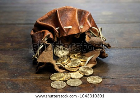 Swiss Vreneli gold coins in a leather purse on rustic wooden background Royalty-Free Stock Photo #1043310301