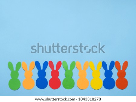 Colorful paper's rabbits on blue background. Happy Easter.
