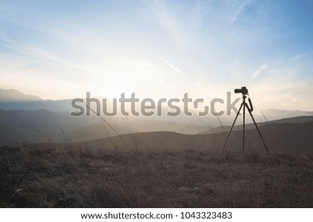 Camera mounted on a tripod, shooting a mountain landscape
