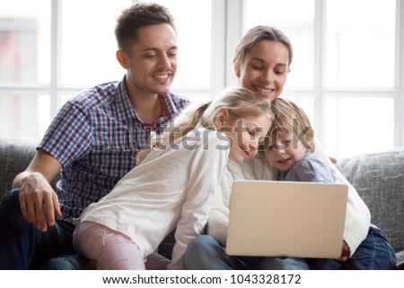Curious cute little children boy and girl peeking on laptop while parents doing online shopping or using computer applications, happy family with son and daughter enjoying leisure at home with pc