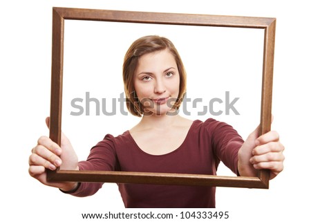 Attractive woman looking through empty wooden picture frame