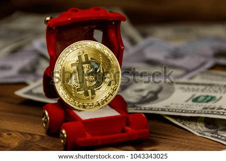 Golden souvenir coin bitcoin in car-shaped gift box for jewelry and dollars on wooden background