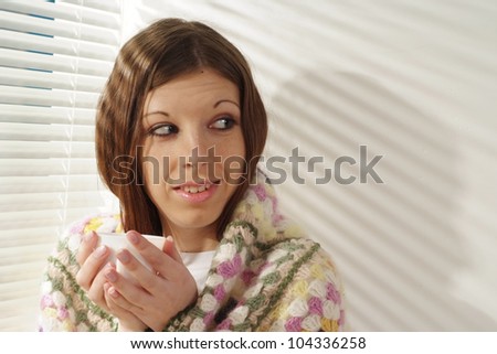 A happy caucasian girl sitting on the carpet against the window
