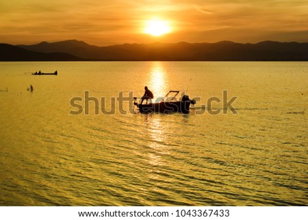 The shadows of the fisherman are on the boat, with mountains and sunsets in the background. Ideas for the background image. Reflection of light.