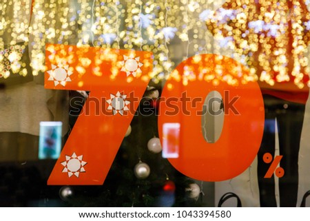 Large Sale 70% discount, a banner on the glass with the reflection of New Year's garlands.