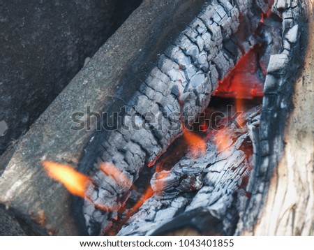 The wooden logs burn in the campfire before cooking a food on a picnic.