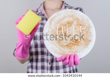 Dish washer concept spot symbol child kid teen age boring mood family dinner ask play work hard concept. Close up photo of girl holding dirty white plate with unhappy face isolated on gray background