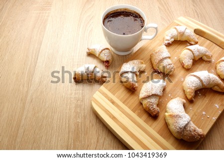 Fresh homemade croissants with cup of coffee on rustic wooden table, copy space for a text