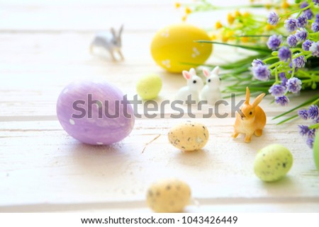 Easter eggs and flowers decoration on rustic wooden background. Vintage style toned picture. Rabbits toys.