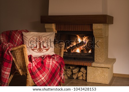 Wool warm blanket or plaid on the background of burning fireplace. Toned.
