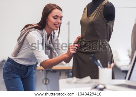 Attractive fashion designer is working with a dress model in her office