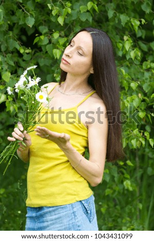Pretty girl with bouquet of daisies on a background of green deciduous forest