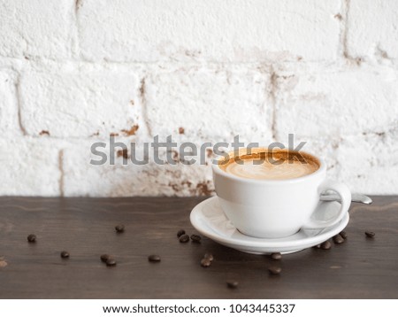 Cup of coffee on wooden table on white brick wall background with copy space.