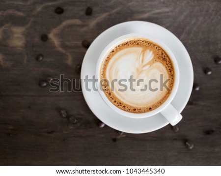 Cup of cappuccino on wooden table on top view.