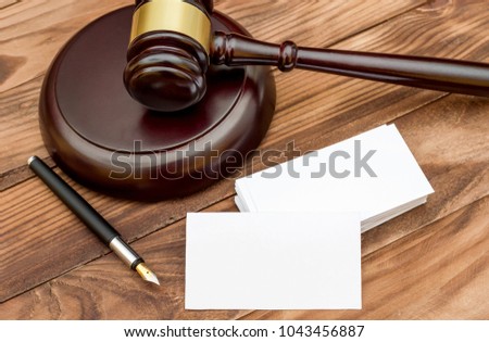 Blank business card with judge's gavel and pen on the table.