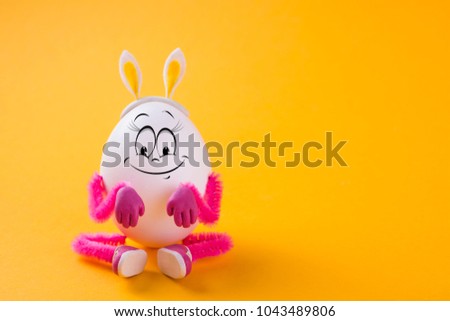 Funny Easter egg girl wearing bunny ears on yellow background. Holiday concept. Copy space.