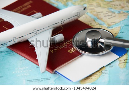 Boarding pass and a passport travel documents with medical stethoscope and airplane on world map background, close-up. Medical travel concept Royalty-Free Stock Photo #1043494024