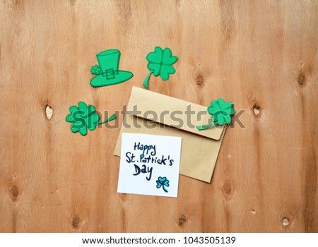 Green Clovers or Shamrocks on rustic wooden background with an envelope with Happy St. Patrick's Day text