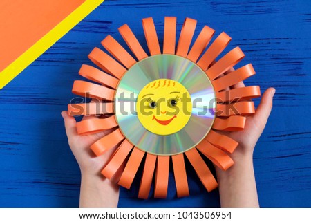 Child makes smiling sun from CD. Children's art project. DIY concept. Step-by-step photo instruction.