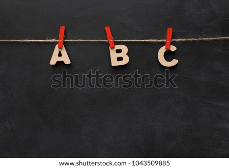 Back to school concept. Alphabet ABC made of wooden letters handing on clothespins on black background, top view, copy space