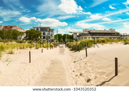 Beach sand, blue sky with clouds, hotels, tall grass. The beach of the Baltic Sea, Germany.
