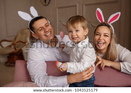 Happy Easter. Young joyful family with child celebrating Easter day. Mother and father wearing bunny ears at Easter sunday