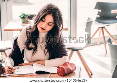 Lifestyle photo of a young student girl at a coffee shop