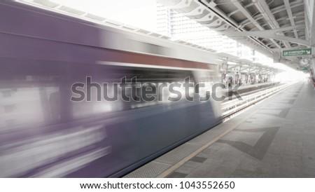 very bright, soft, blurry shot of sky train moving forward after picking up passengers at station platform at about noon time (Bangkok, Thailand) 