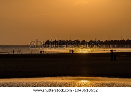 Happy family walking on sea coast. Silhouettes sunset.