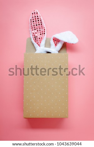 Table top view aerial image of decoration & symbol Happy Easter holiday background concept.Flat lay accessory costume bunny ear with paper bag on modern beautiful pink paper at home office desk.