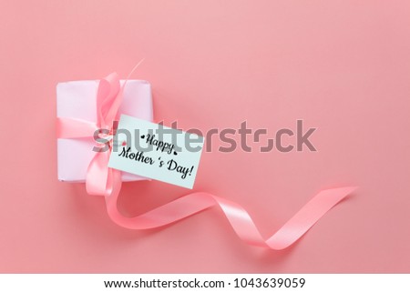 Top view aerial image of decoration Happy mother’s day holiday background concept.Flat lay mom white card with gift box on modern beautiful  pink paper at home office desk.Free space for design.