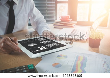 Businessman working with digital tablet and book and document on wooden desk in modern office.Toop view Business analysis and strategy concept.