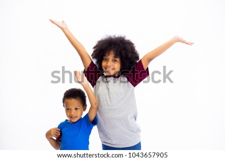 Smiling young African American sister and brother raising hands isolated over white background