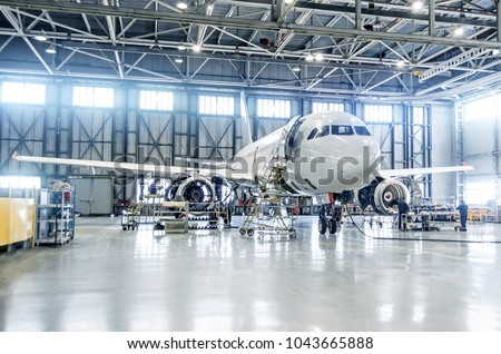 Passenger airplane on maintenance of engine and fuselage check repair in airport hangar Royalty-Free Stock Photo #1043665888