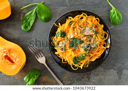 Butternut squash spirilized noodles with spinach and pumpkin seeds on dark slate background, Healthy eating concept. Top view, table scene. Royalty-Free Stock Photo #1043673922