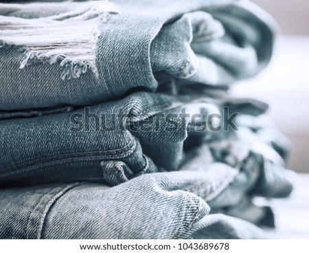 Folded stack of jeans on a wooden background, concept of stylish clothes