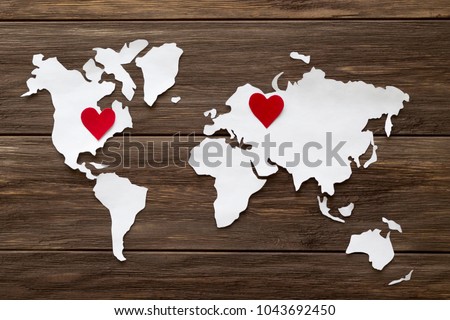 Red felt hearts and world map cutted from white paper on the wooden background. Long-distance relationships concept - Russia and United States. Flat lay, top view, copy space, mock up Royalty-Free Stock Photo #1043692450